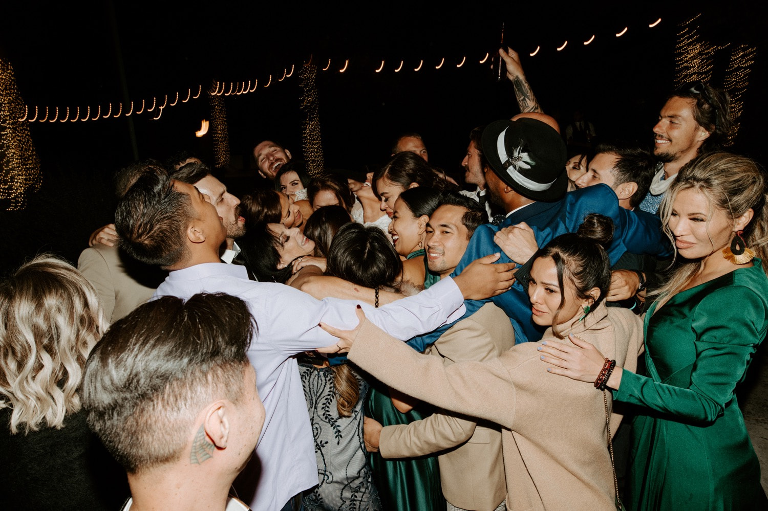 Joan and Kyle's guests crowd together on the dance floor under string lights