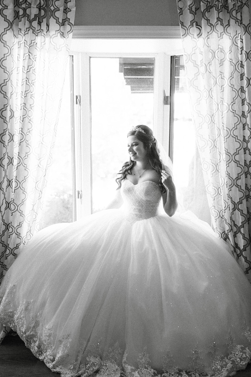Montse sits by a window in her ball gown before the ceremony at Tannenbaum
