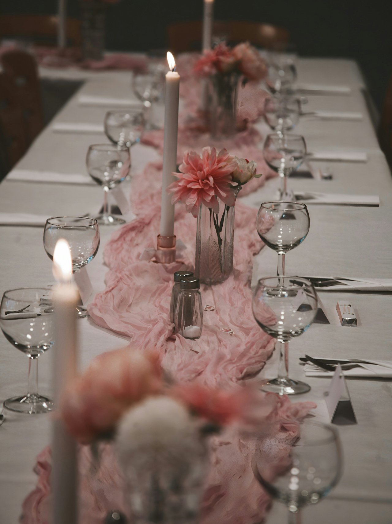 A long table set in pink and white with candles, flowers and wine glasses for Alice’s party