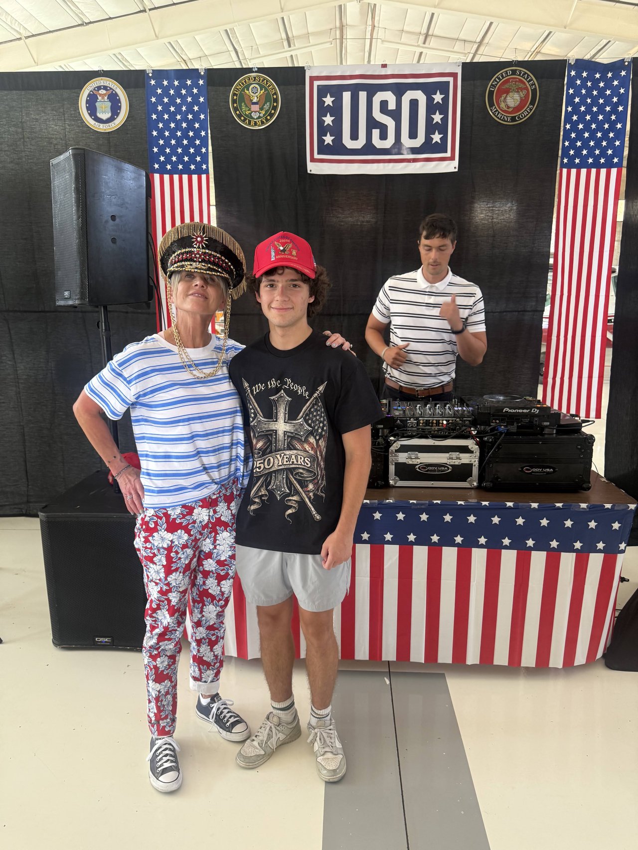 A guest in a captain’s hat and a teen in a 250 years tee smiling at the USO stage