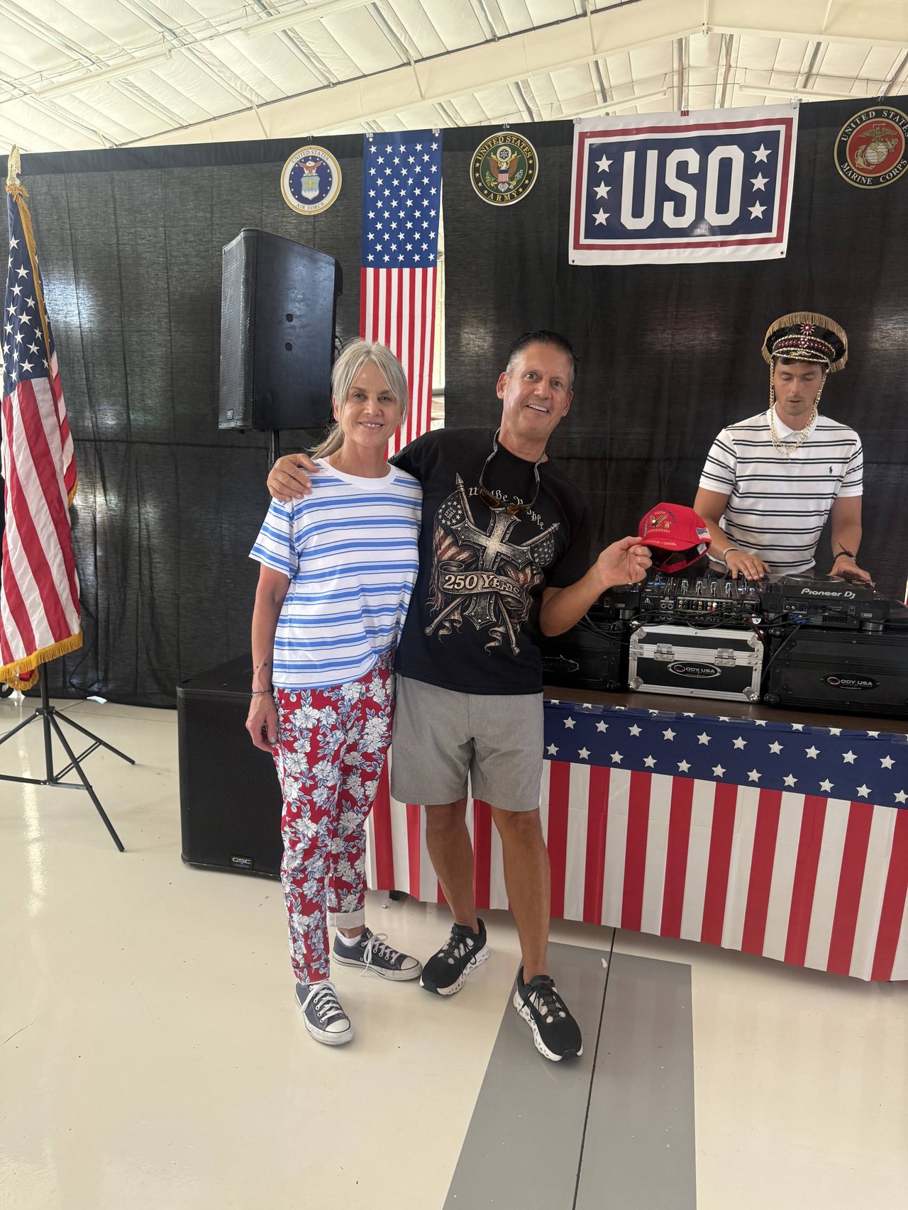 Three guests in red, white and blue posing in front of the USO stage and DJ booth