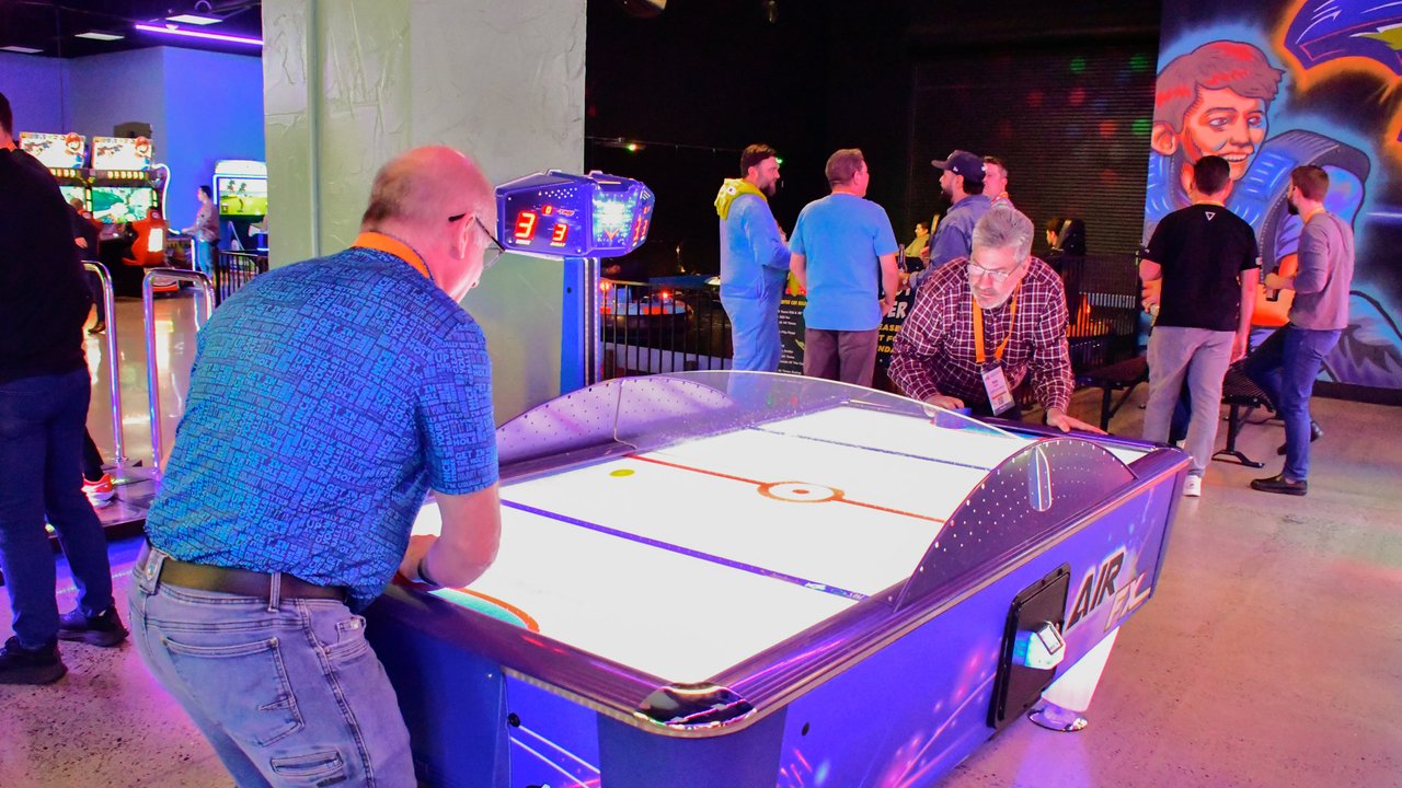 AMUG guests playing air hockey under the arcade lights