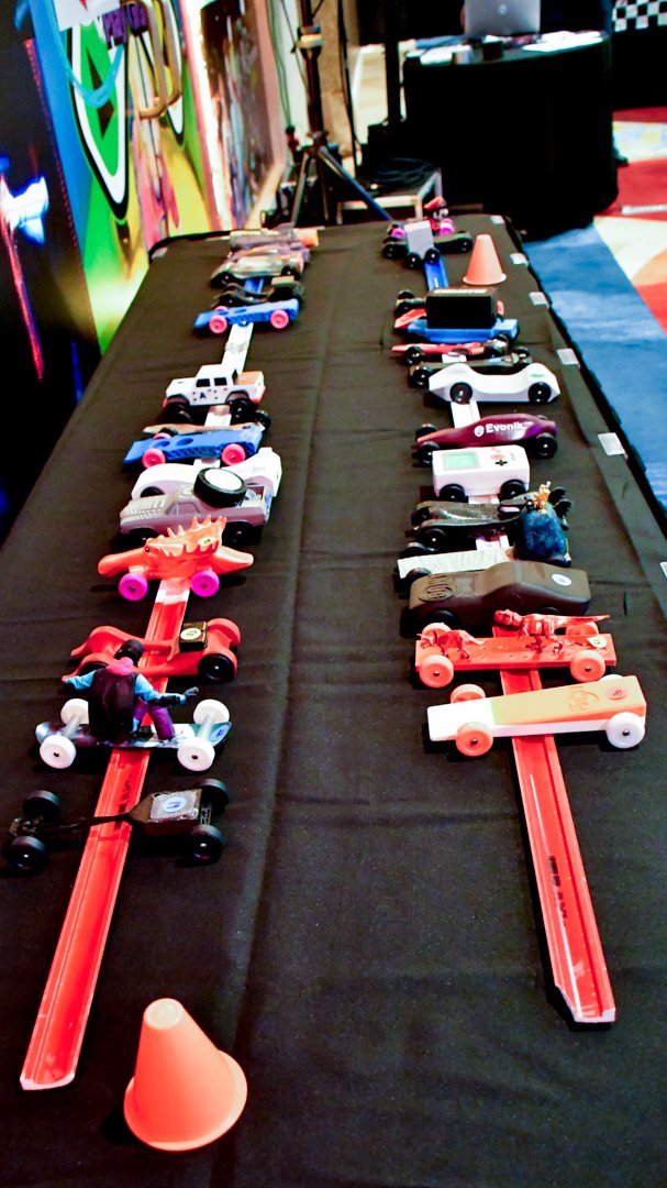 Rows of decorated derby cars lined up on a table waiting to race