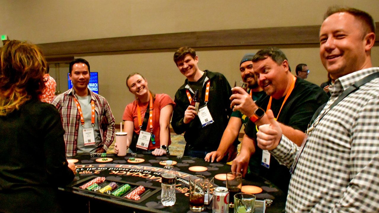 A group of AMUG guests smiling around a blackjack table