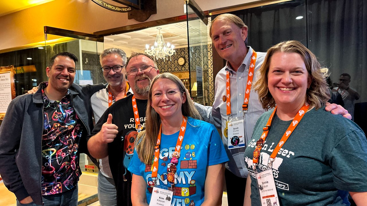 Six AMUG guests in game shirts and lanyards smiling together