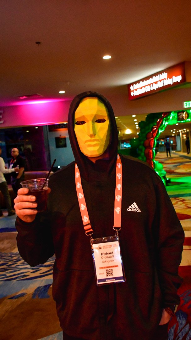 An AMUG guest in a gold mask and a black hoodie raising a drink