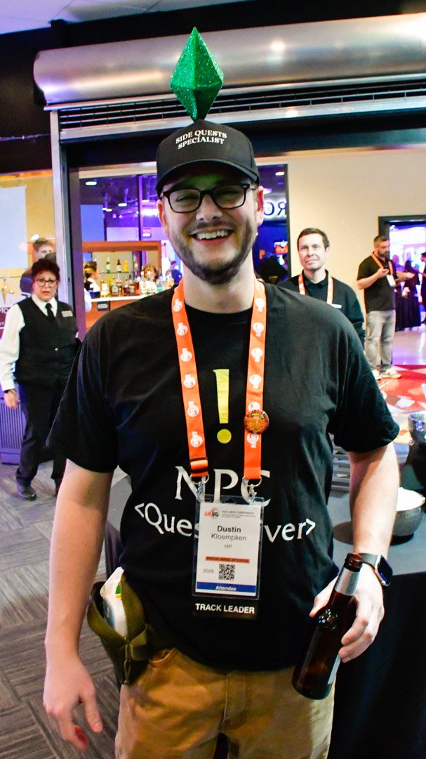 A smiling AMUG guest in an NPC shirt with a green diamond on his hat
