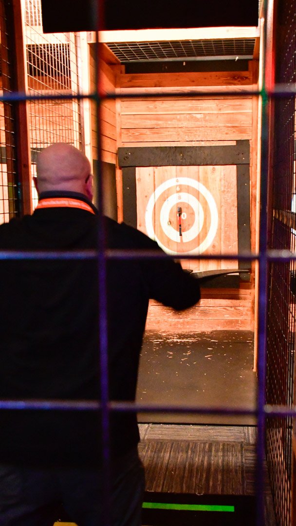 An AMUG guest throwing an axe at a bullseye target in the axe throwing lane