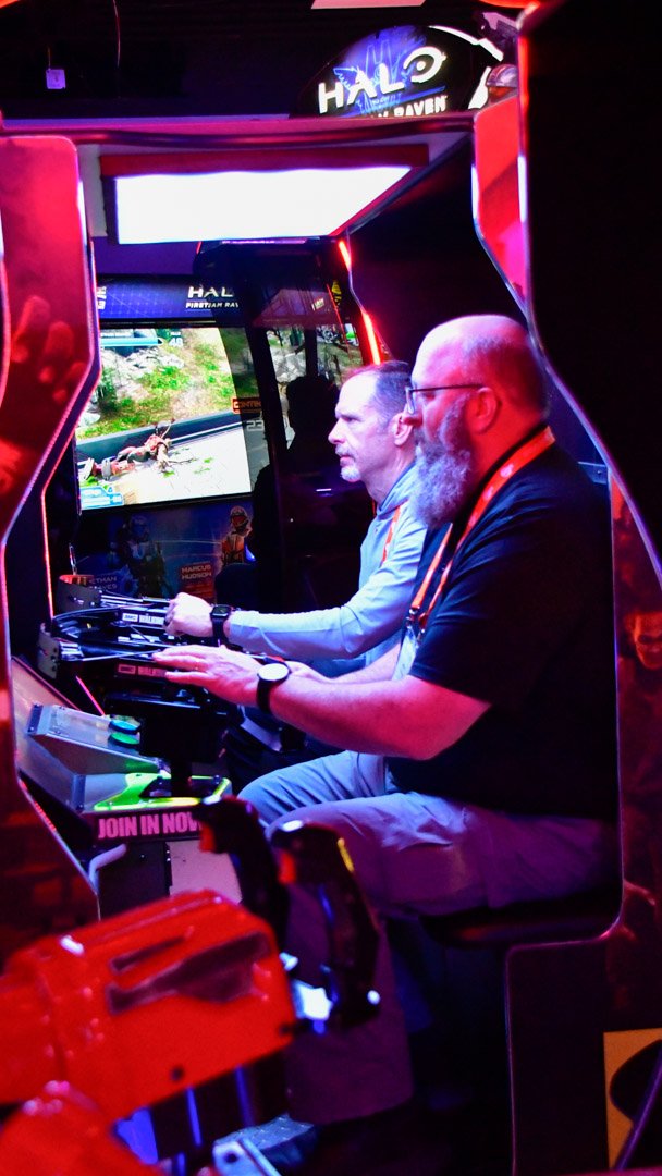 Two AMUG guests playing inside a Halo arcade cabinet