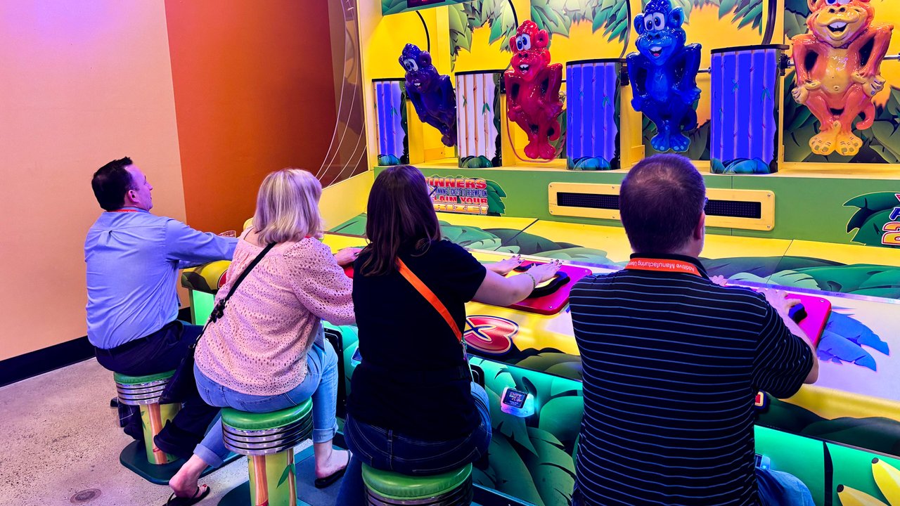 Four AMUG guests seated at a colorful carnival arcade game