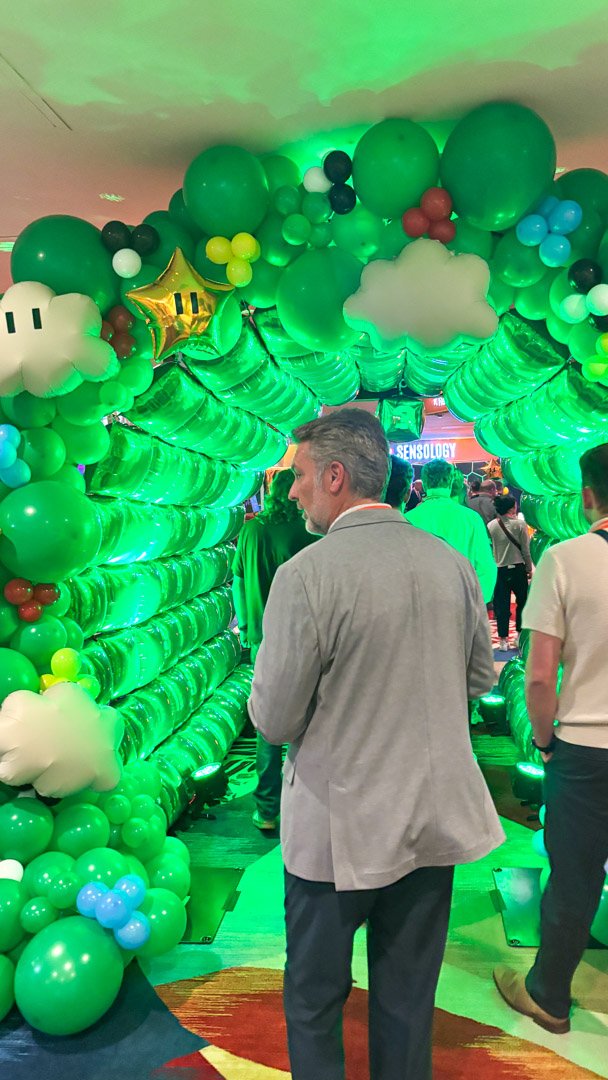 AMUG guests walking through the green balloon arch tunnel with clouds and stars