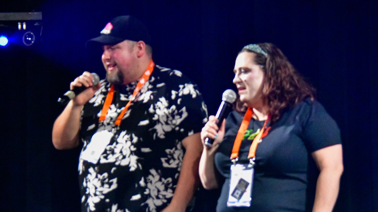 Two AMUG guests singing a karaoke duet on the stage