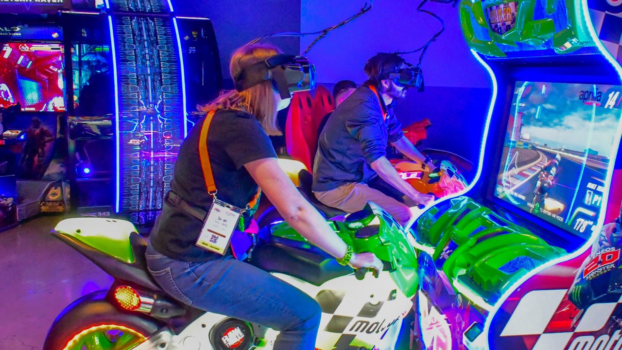 Two AMUG guests racing on motorcycle arcade games