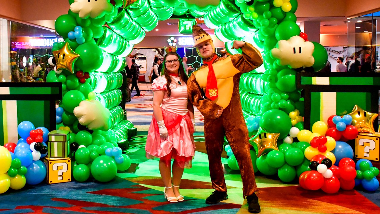 Princess Peach and Donkey Kong posing in front of the green balloon arch