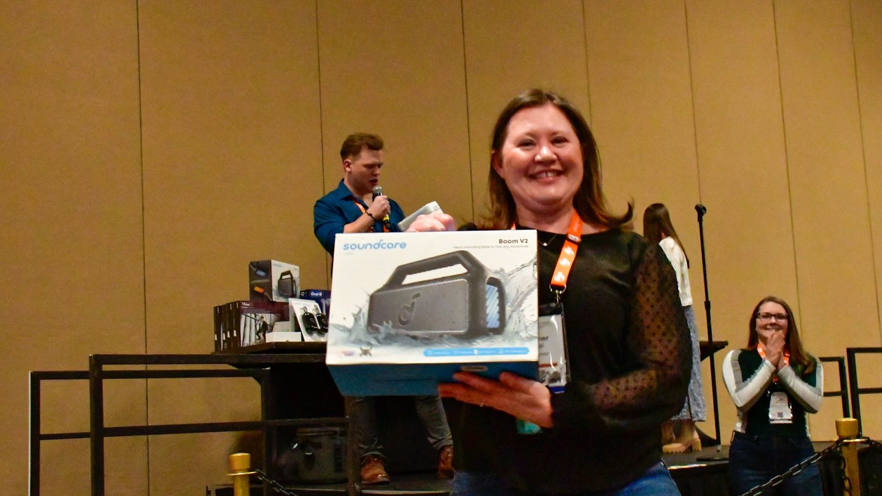 An AMUG guest smiling with the speaker she won in the raffle