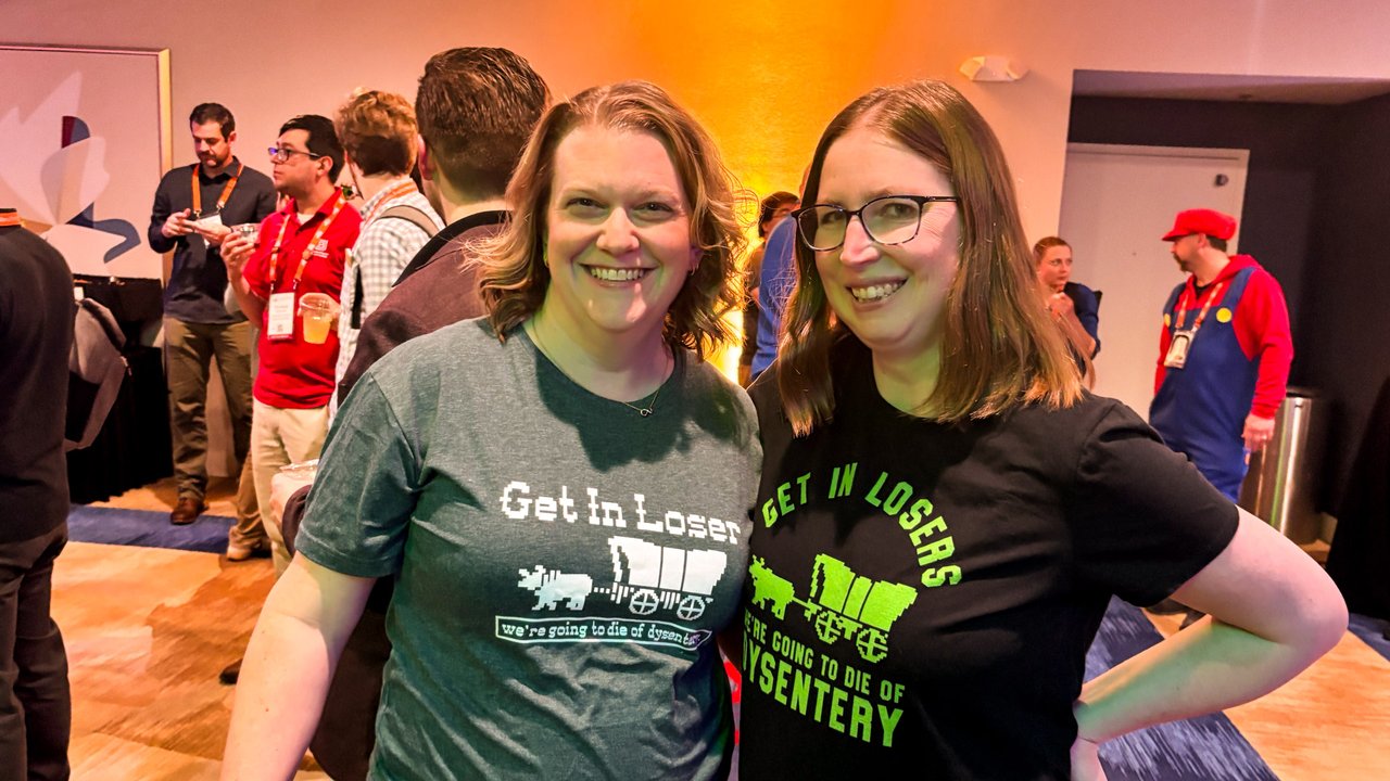 Two smiling AMUG guests in matching retro game shirts in the crowd