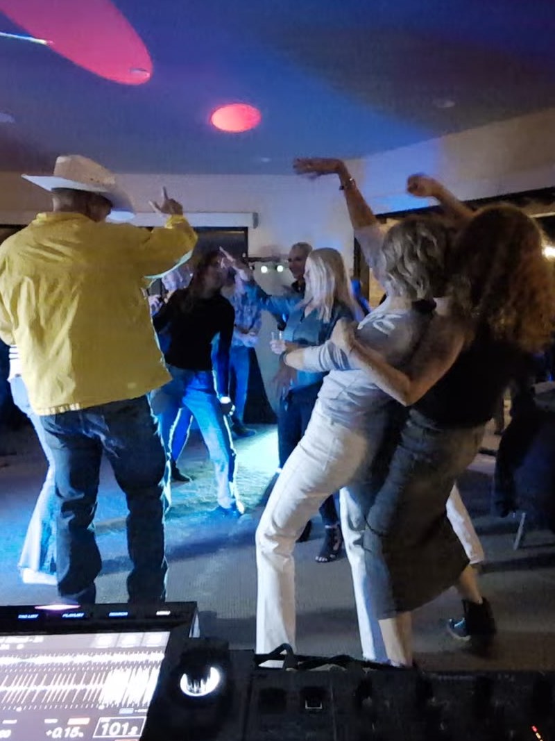 A guest in a cowboy hat and yellow jacket dancing in front of the DJ booth at John Sullivan’s 50th birthday