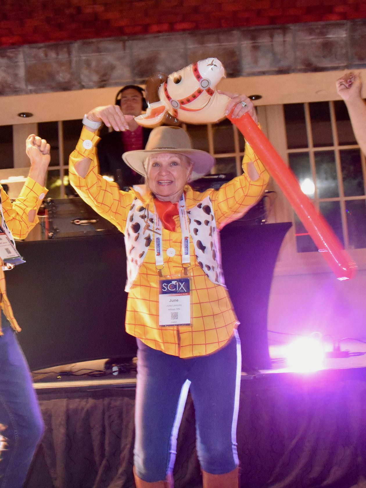 SciX Gala guests in cowboy costumes dancing with a stick horse in front of the DJ booth