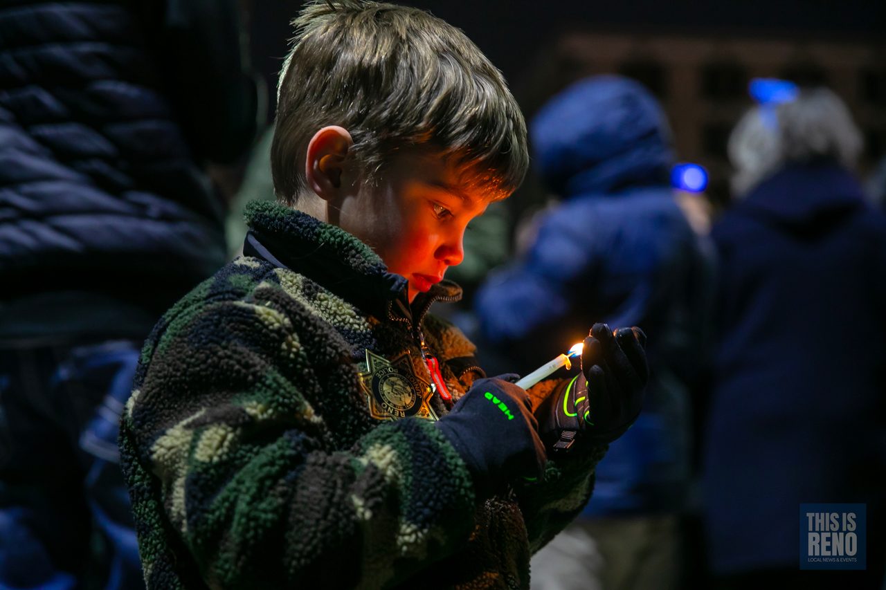 A boy holding a lit candle in the crowd