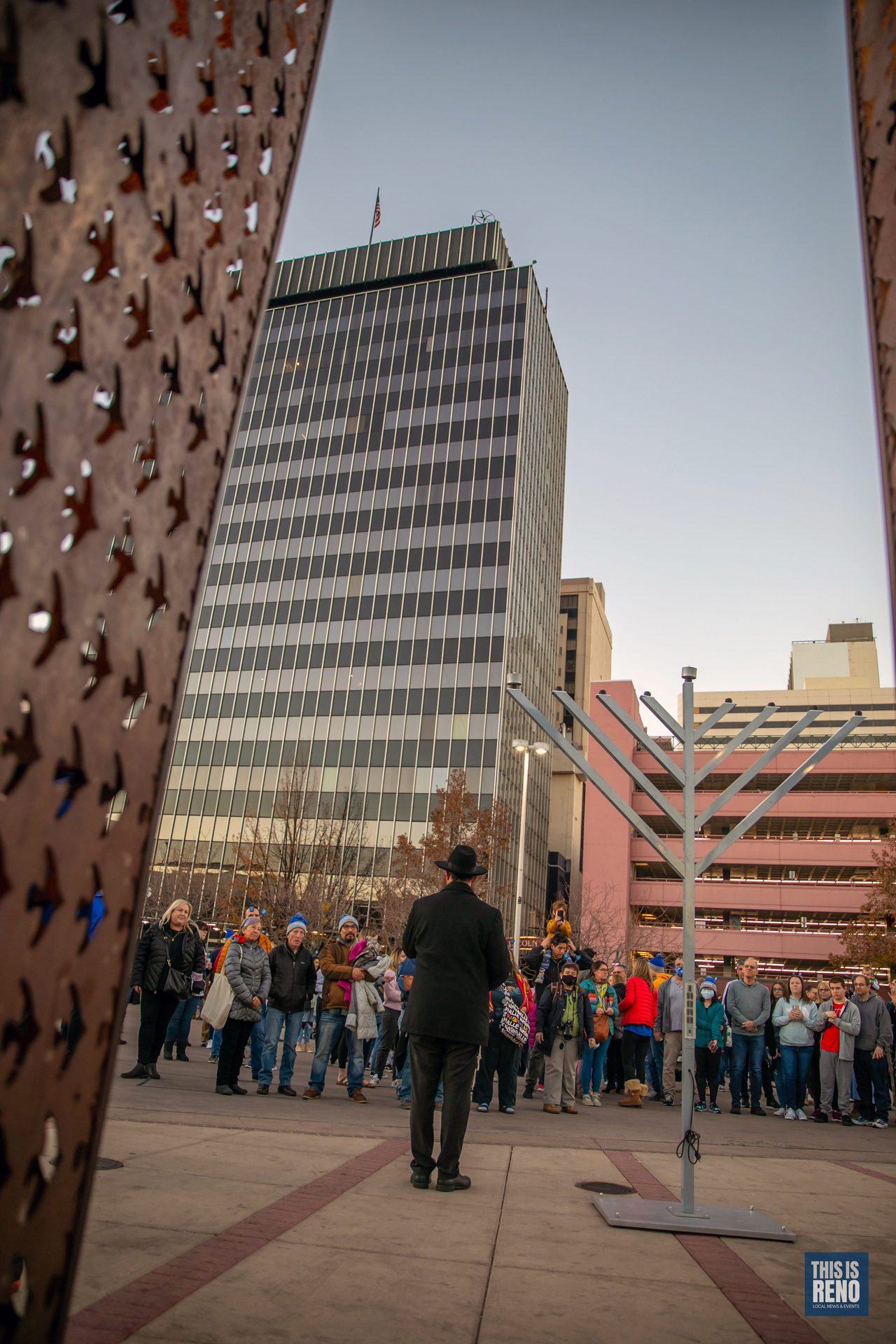 The crowd around the menorah, seen through the City Plaza sculpture