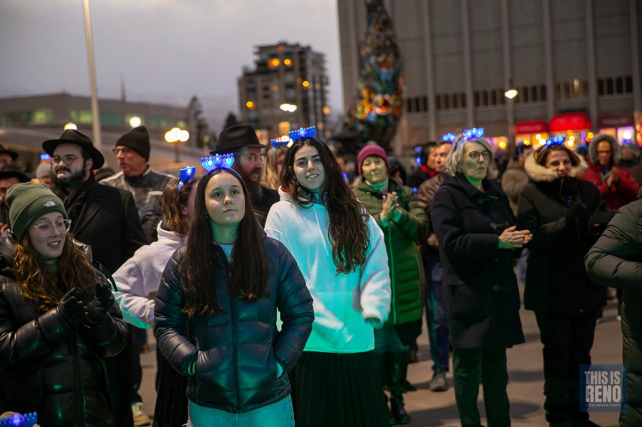 Guests in light up menorah headbands wait in the crowd