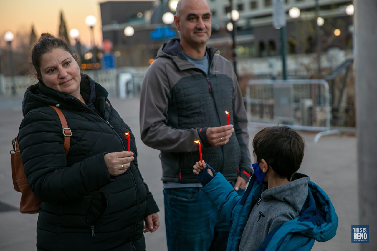 A family holding lit candles at the Menorah Lighting
