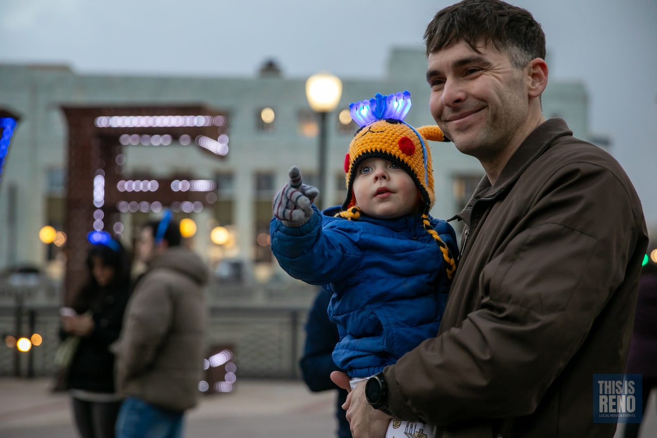 A father holding his son in a menorah headband in City Plaza