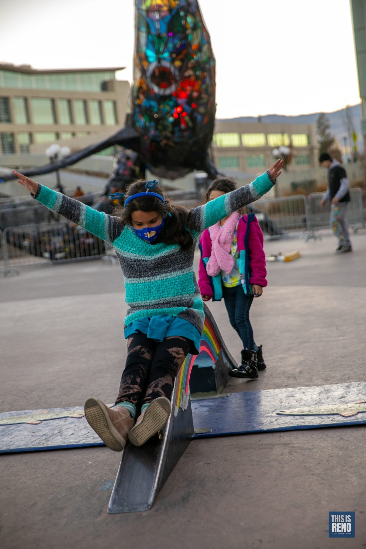 A girl stretches her arms out on the City Plaza sculpture as families arrive