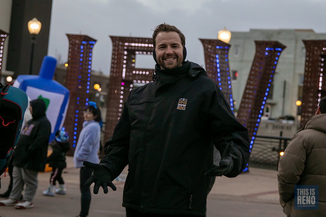 A guest smiles and waves by the Believe sign