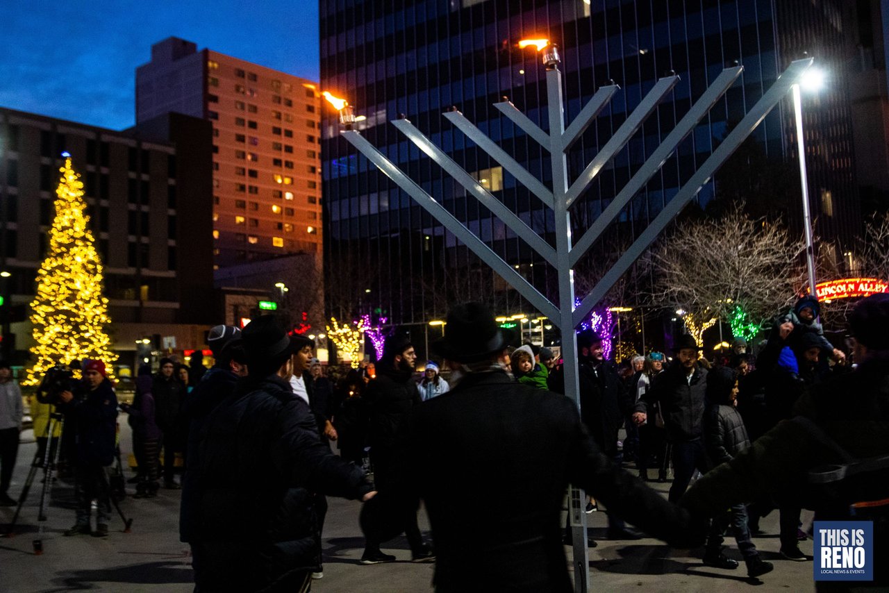 Dancers join hands in a hora around the giant menorah