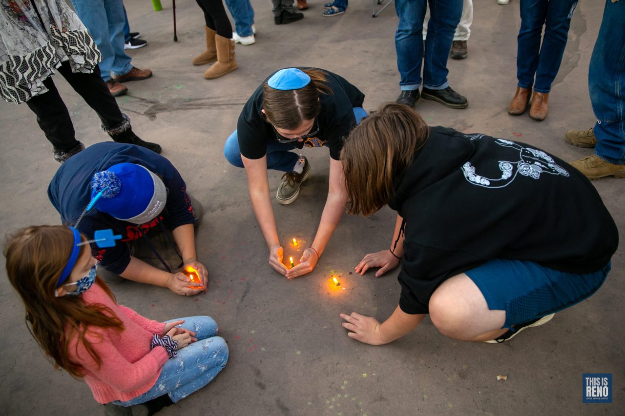 Kids lighting small candles on the plaza