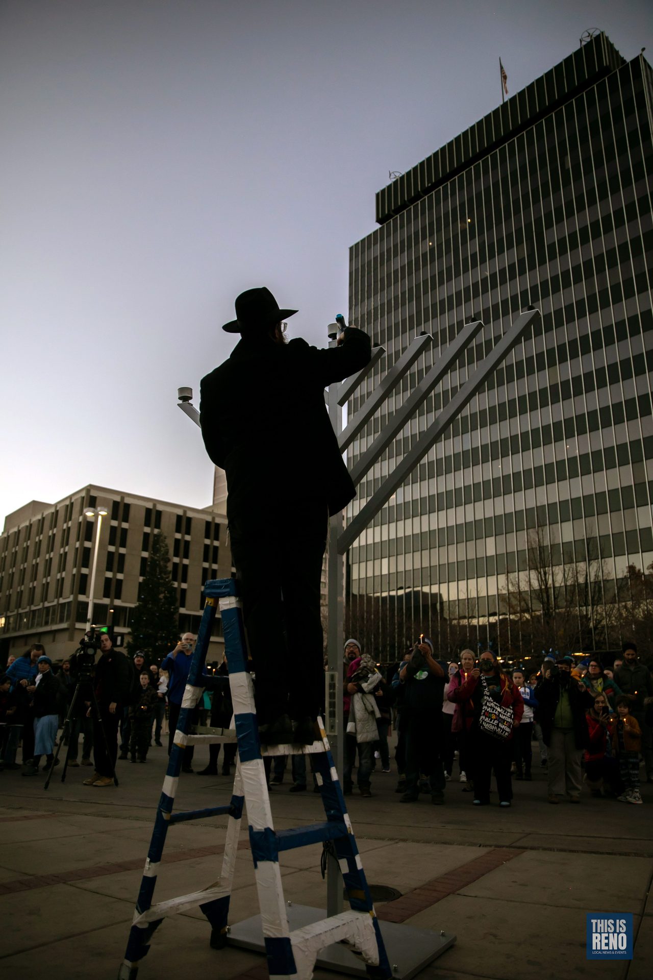 Lighting the menorah from the ladder above the crowd