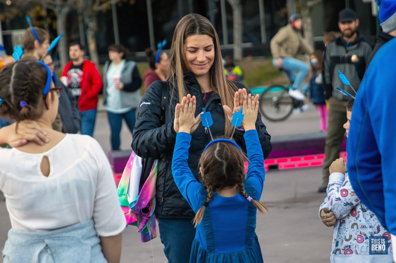 A mother and daughter share a high five in City Plaza before the Chanukah Menorah Lighting