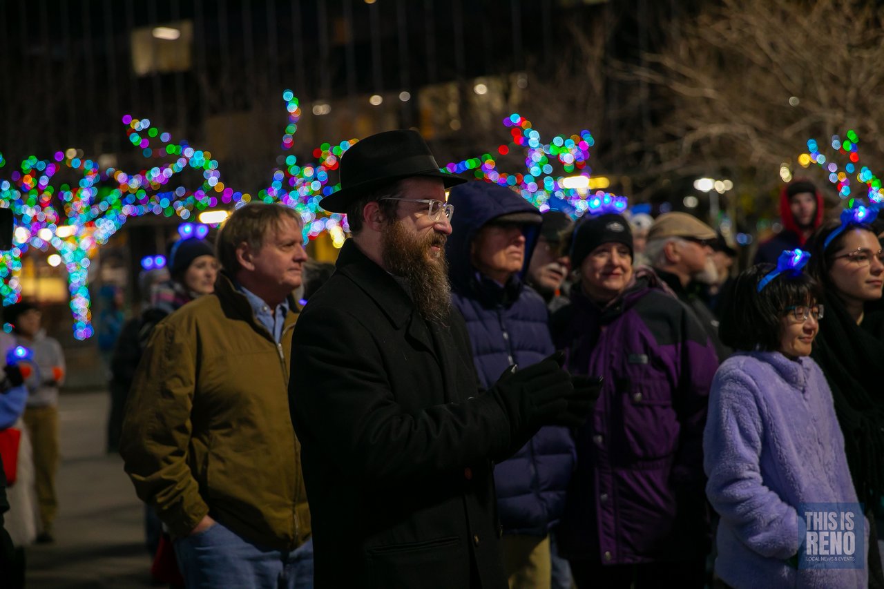A rabbi stands among guests under the colored lights
