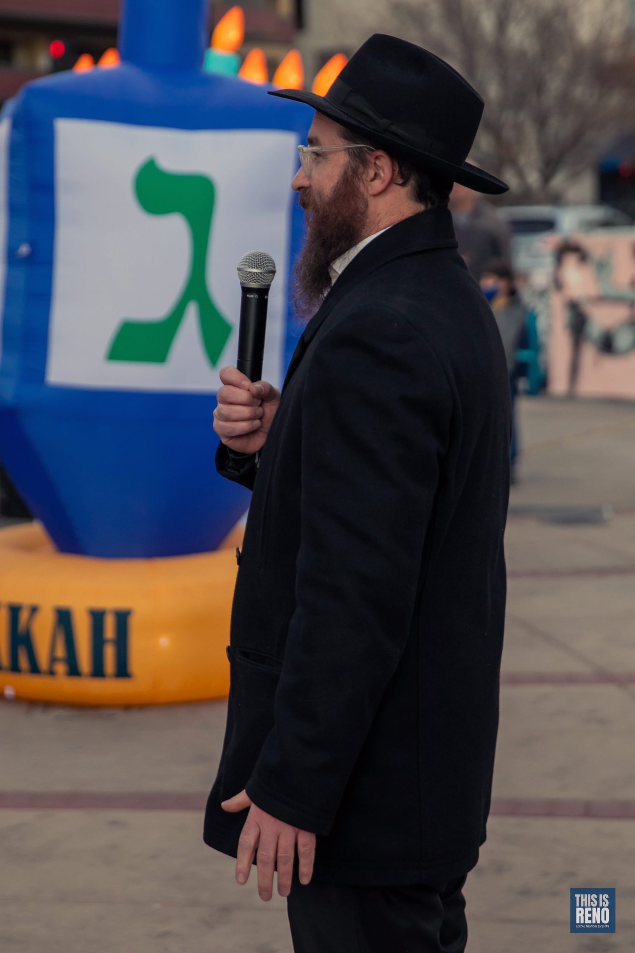 A rabbi speaking beside a giant inflatable dreidel
