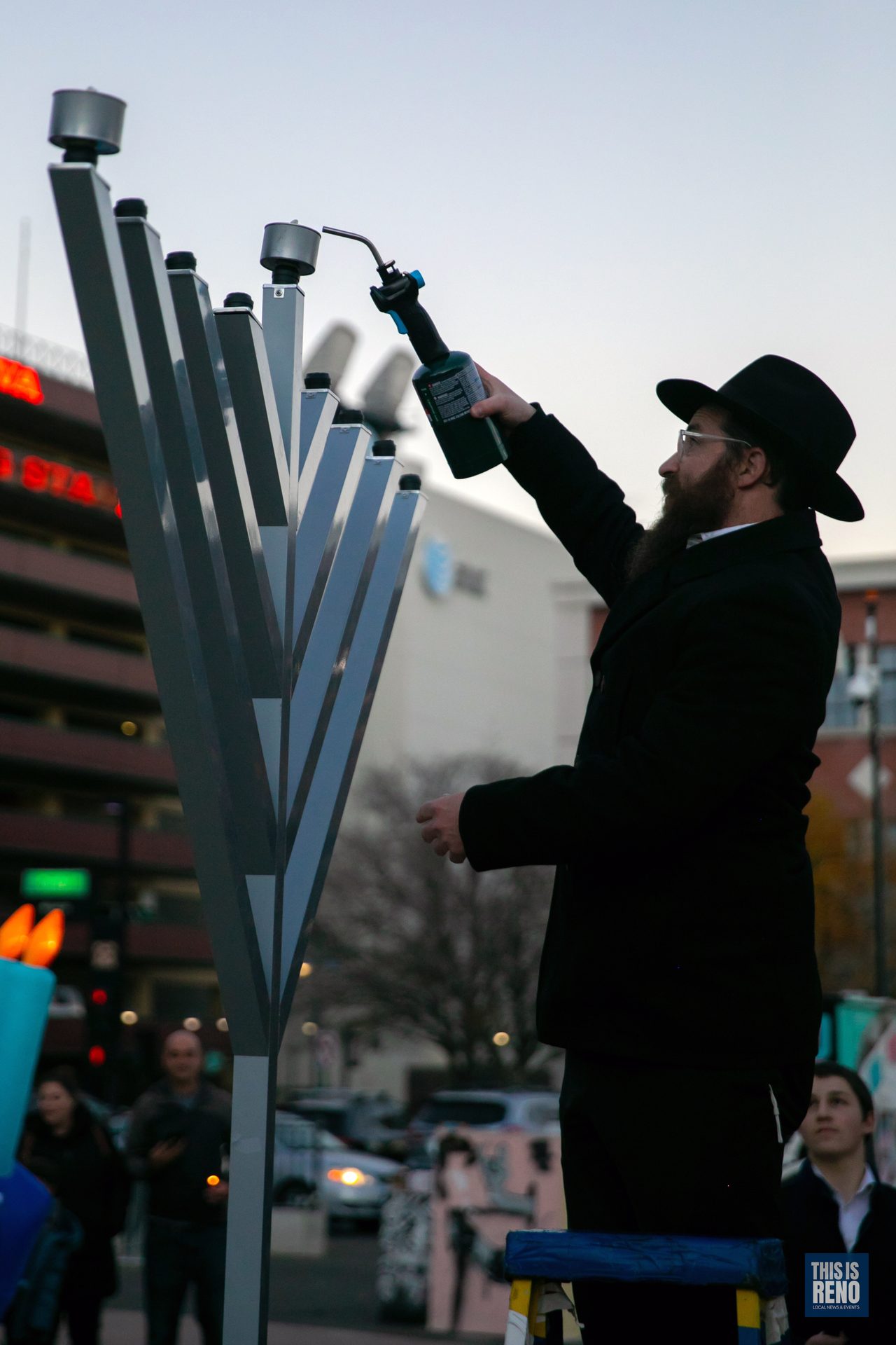 A rabbi lighting the menorah at dusk