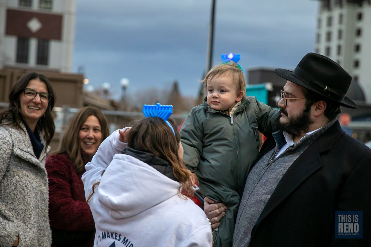 A rabbi with family and friends, the baby in a menorah headband