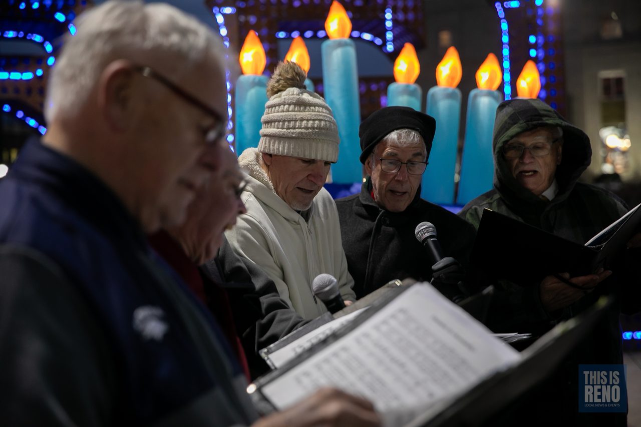 Singers reading their music beside the glowing candles