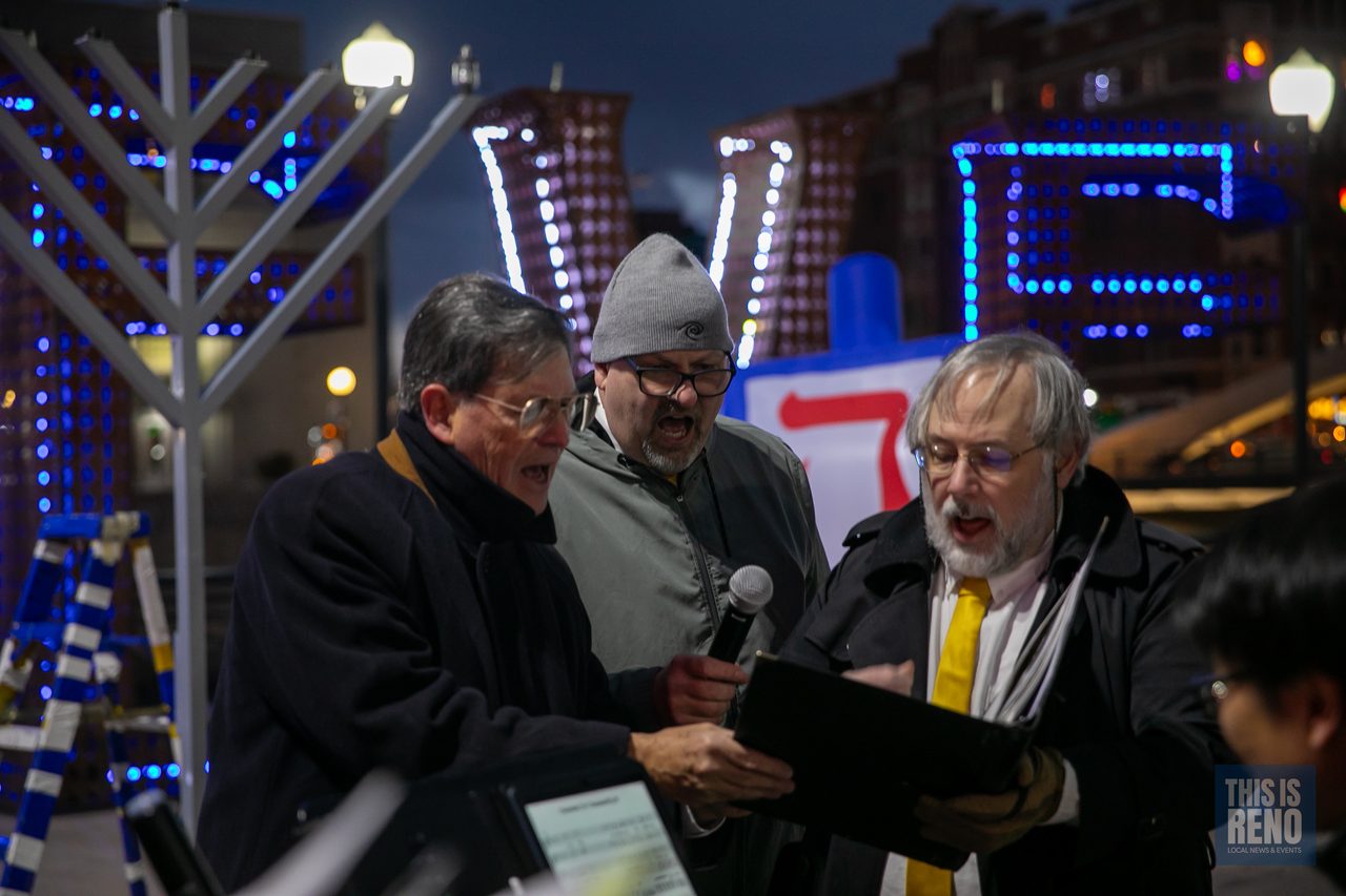 Speakers reading together beside the menorah
