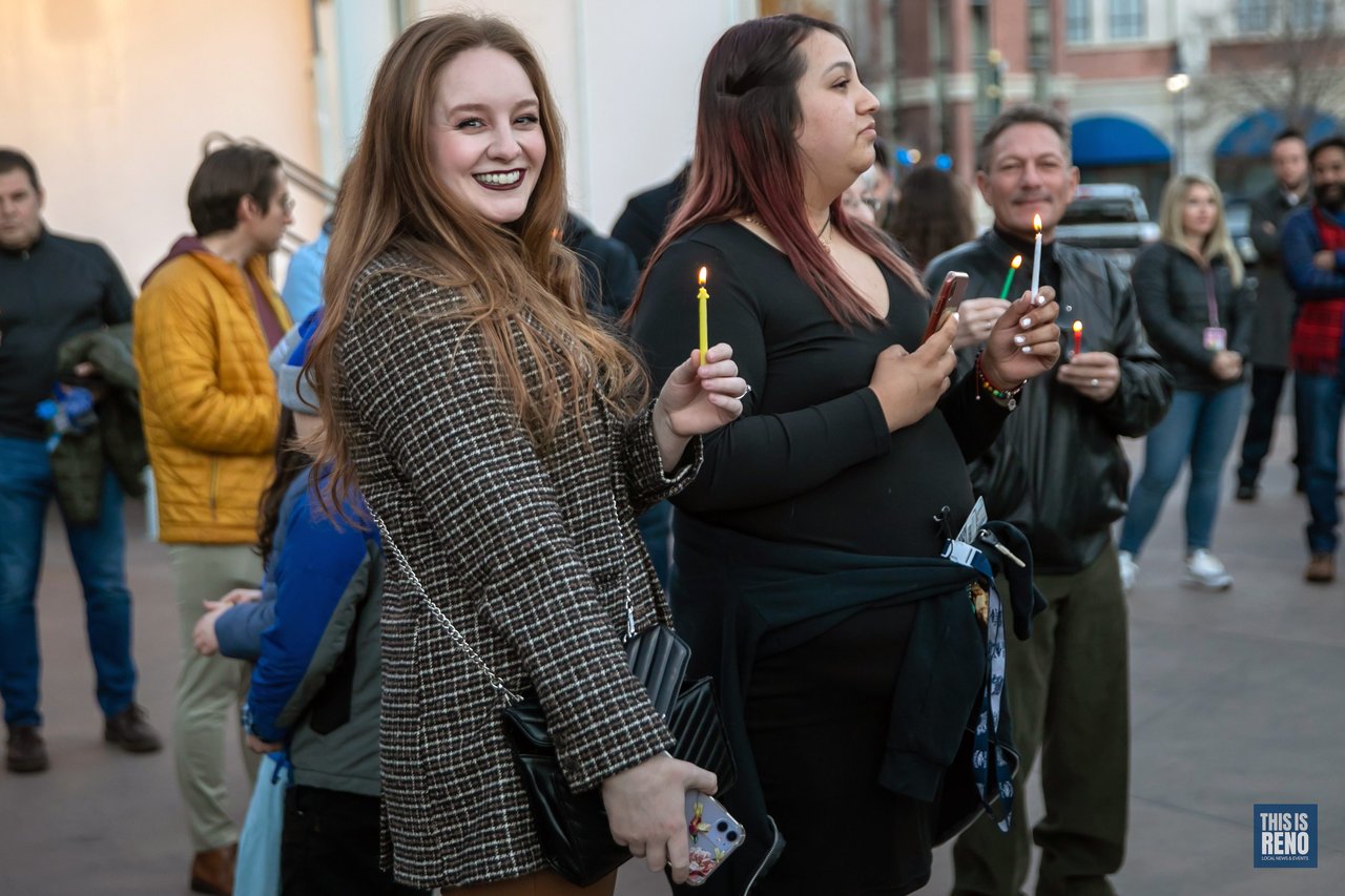 Two women smile as they hold their lit candles
