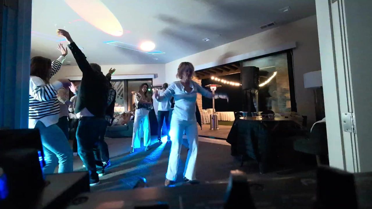 Guests with their arms up under the party lights