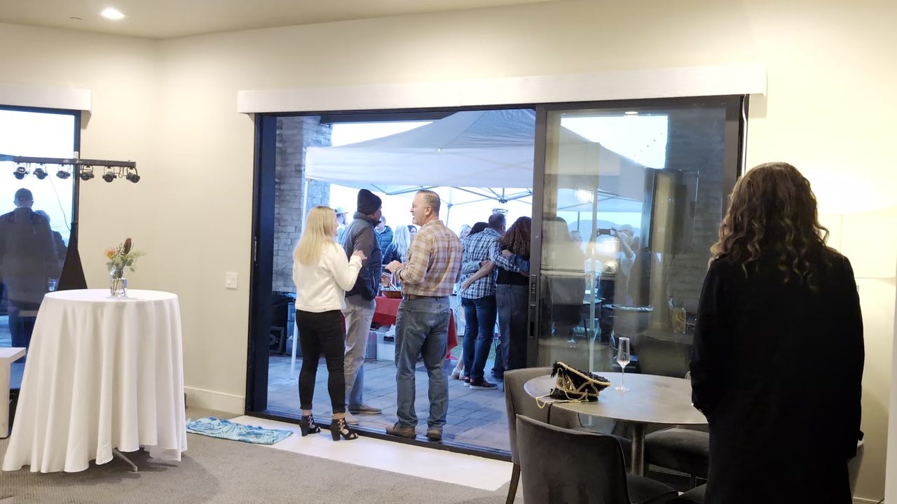 Guests talking by the open glass doors with the tent outside