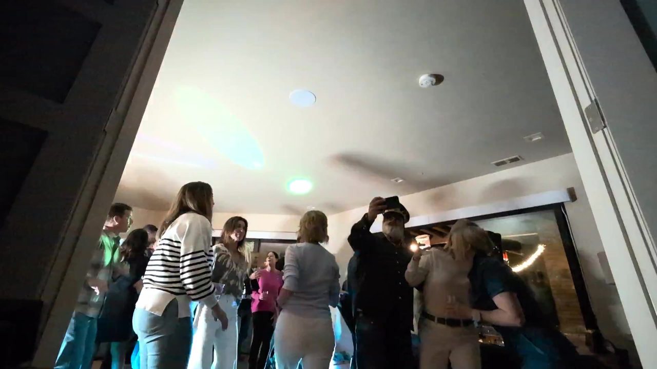 Guests dancing by the patio doors with the string lights outside