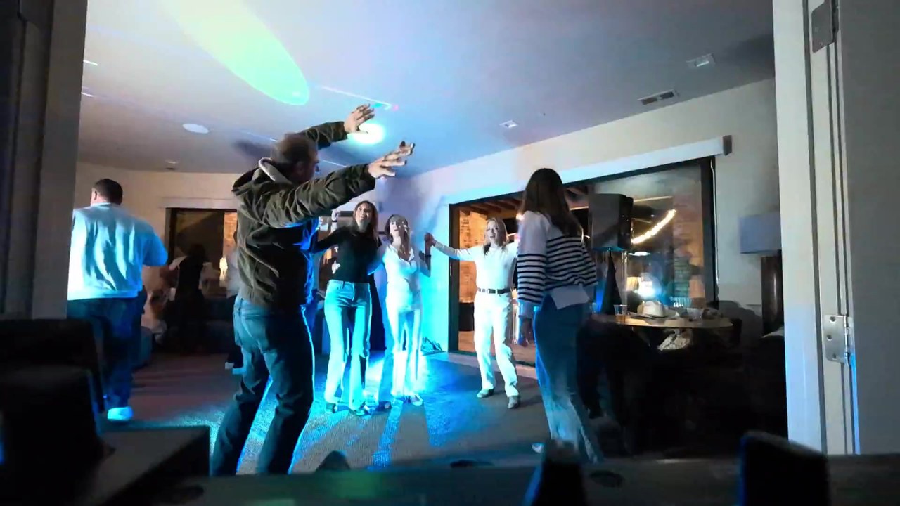 Guests dancing under the lasers and party lights in the living room