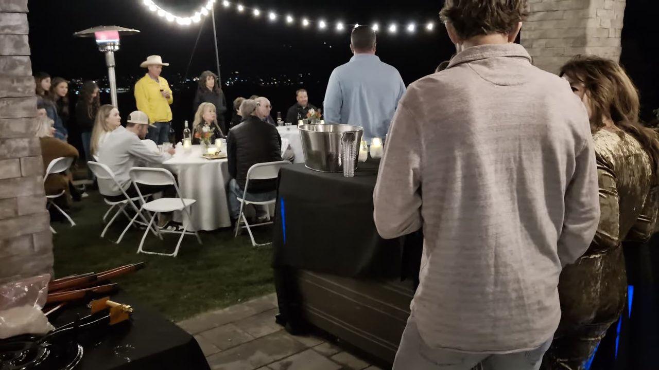 Guests on the lawn under the string lights and patio heaters at night