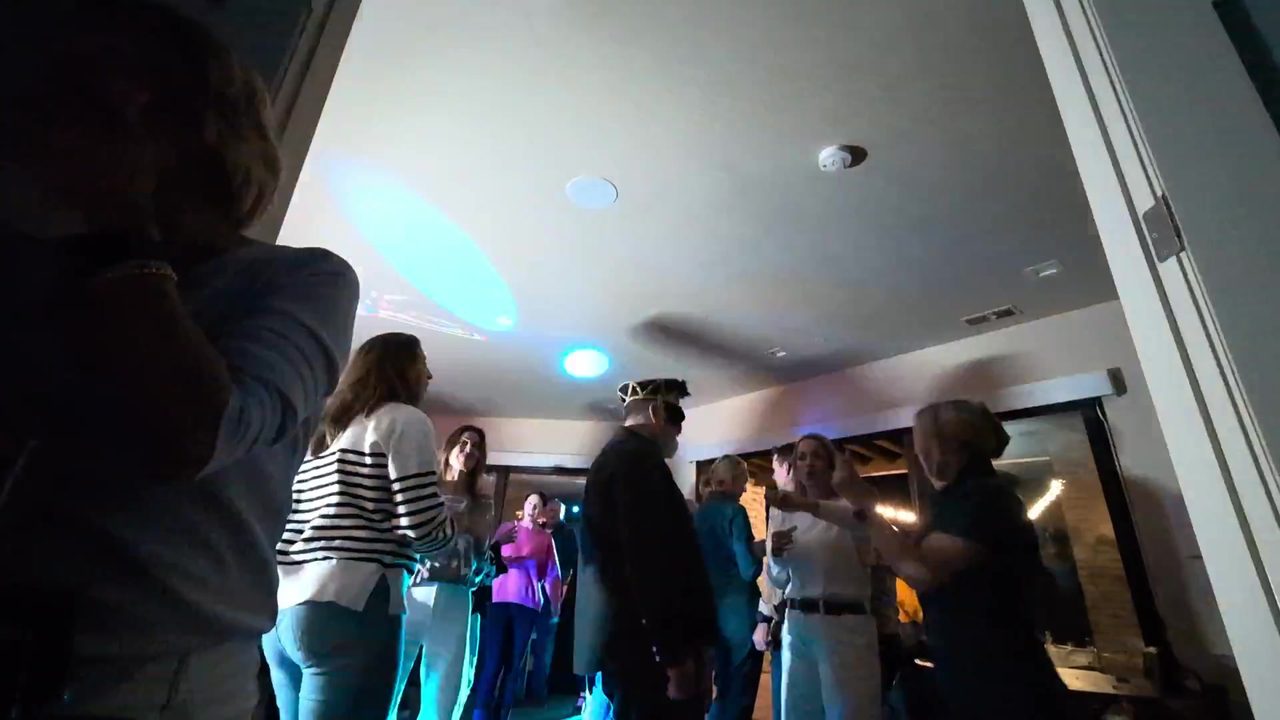 A packed dance floor in the living room under blue lights