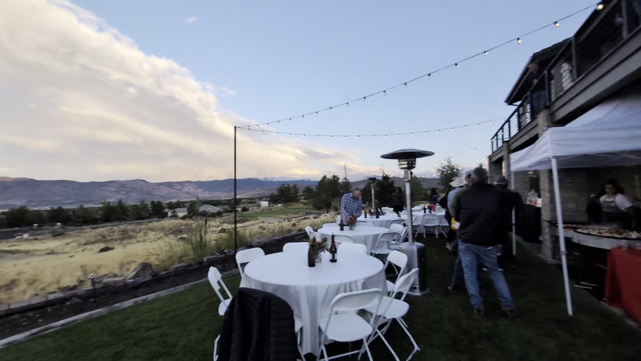 Round tables, string lights and the tent on the lawn at golden hour