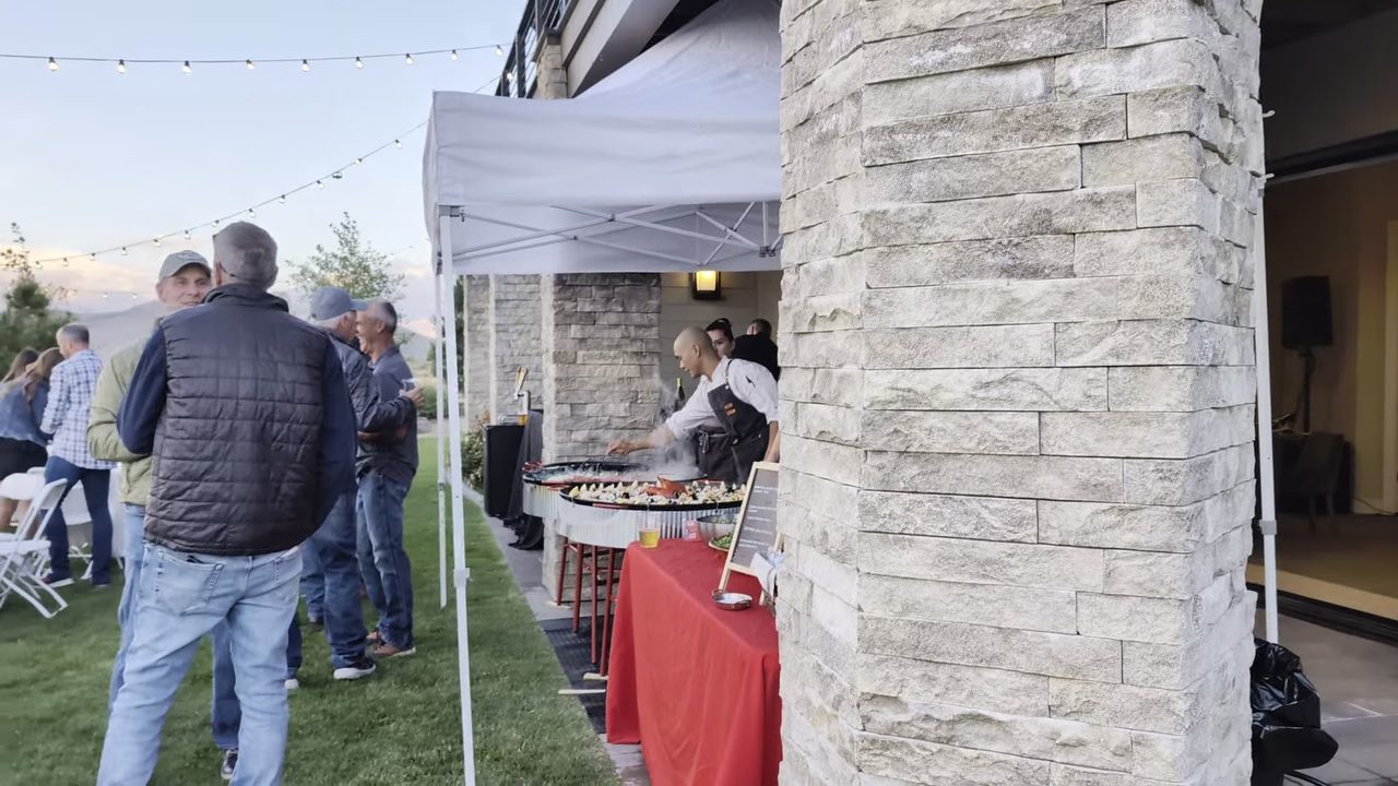 Guests gathering at the paella tent beside the stone columns