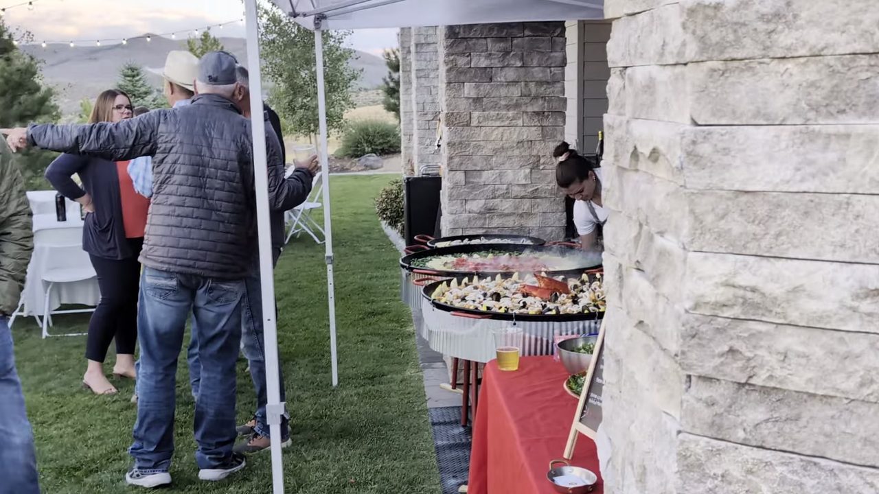 Guests lining up as the paella is served under the tent
