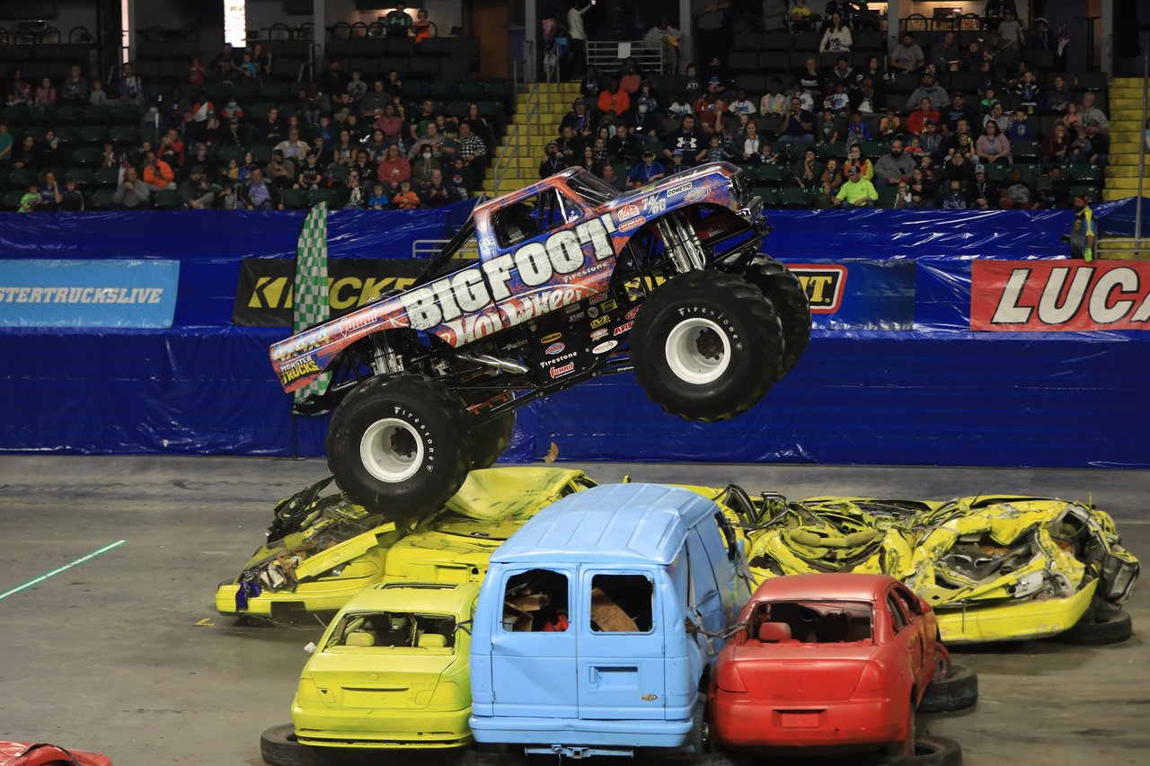 Bigfoot in the air over a row of crushed cars in front of the stands